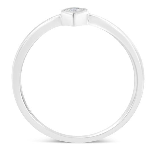 Top-down view of a white metal ring with a single round white gemstone in a bezel setting.