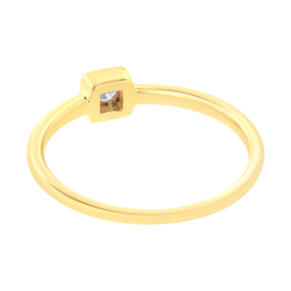 Yellow metal ring with a round white gemstone in a square setting, shown at an angled close-up.