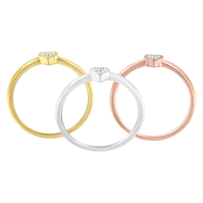 Front-facing view of three rings in yellow, white, and rose metal colors, each featuring a small heart-shaped setting with three round white gemstones.