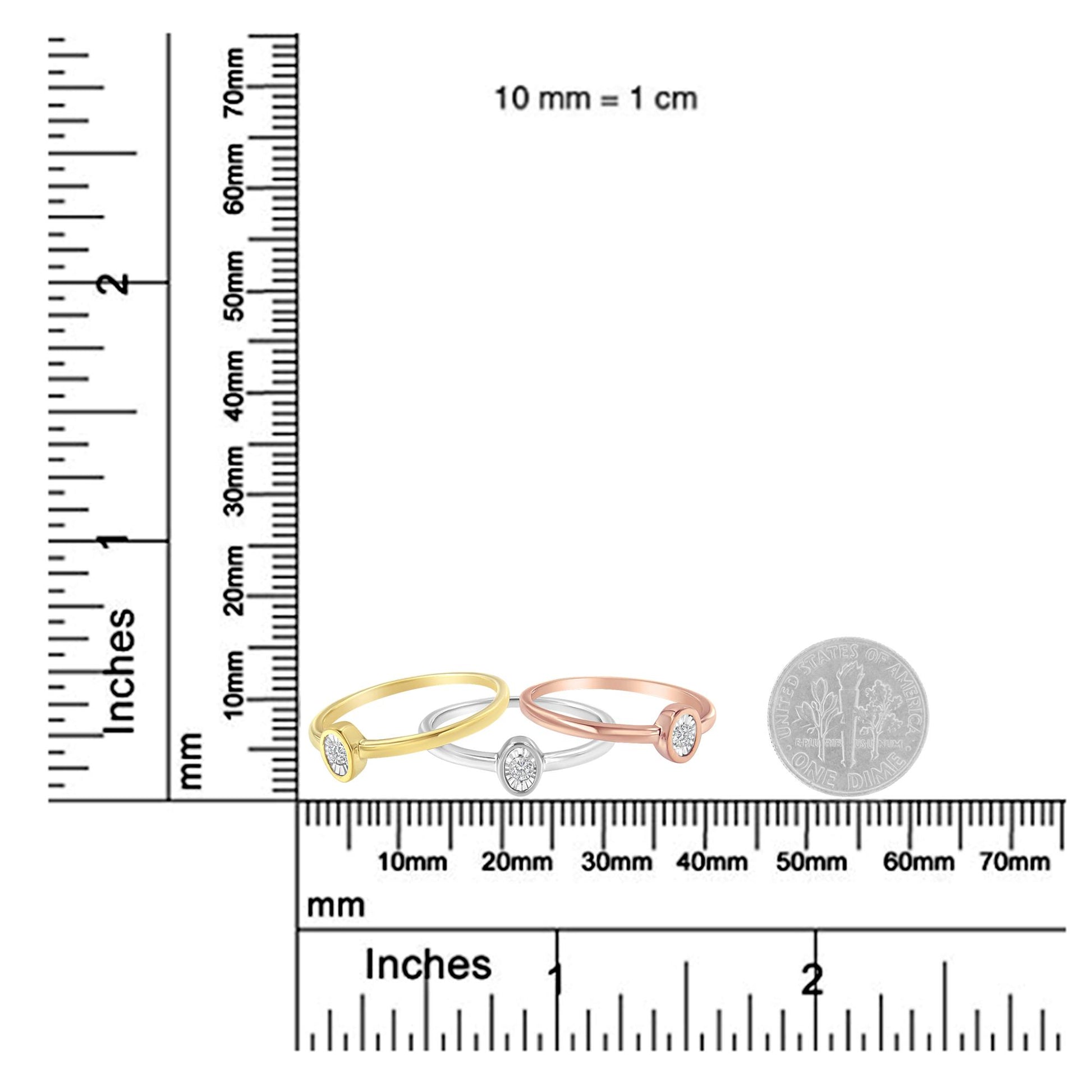 Three rings in yellow, white, and rose metal colors with round white gemstones in miracle settings, displayed on a ruler and scale for size reference, shot from the front angle.