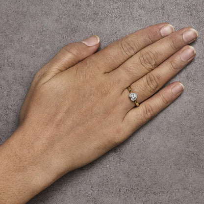 Ring with yellow and white metal featuring a cluster of white round gemstones in prong settings, worn on a model's hand, top-down angle.