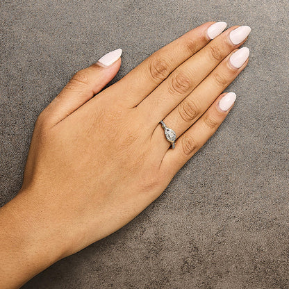 Yellow metal ring with a twisted design and round white gemstones in prong settings, shown worn on a model's hand from a top-down angle.