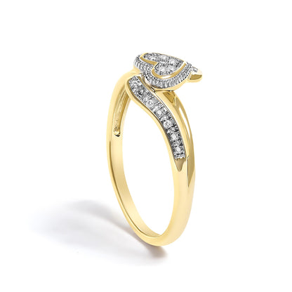 Yellow metal ring with a curved band featuring a row of white round pave-set gemstones and a heart-shaped cluster of white round pave-set gemstones, shown at an angled front view.