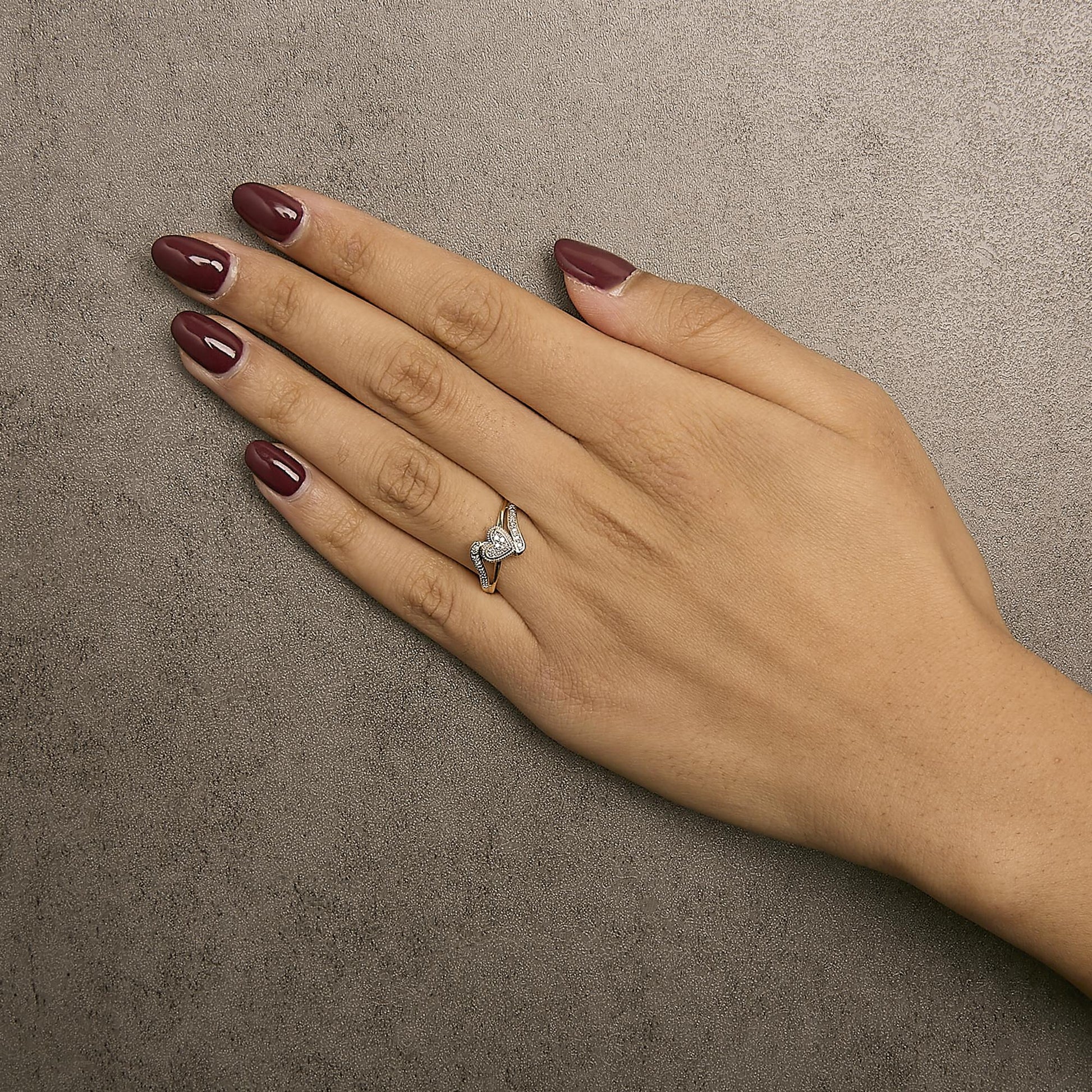 Yellow metal ring with round white gemstones in pave setting, shown worn on a model's hand, top-down angle.