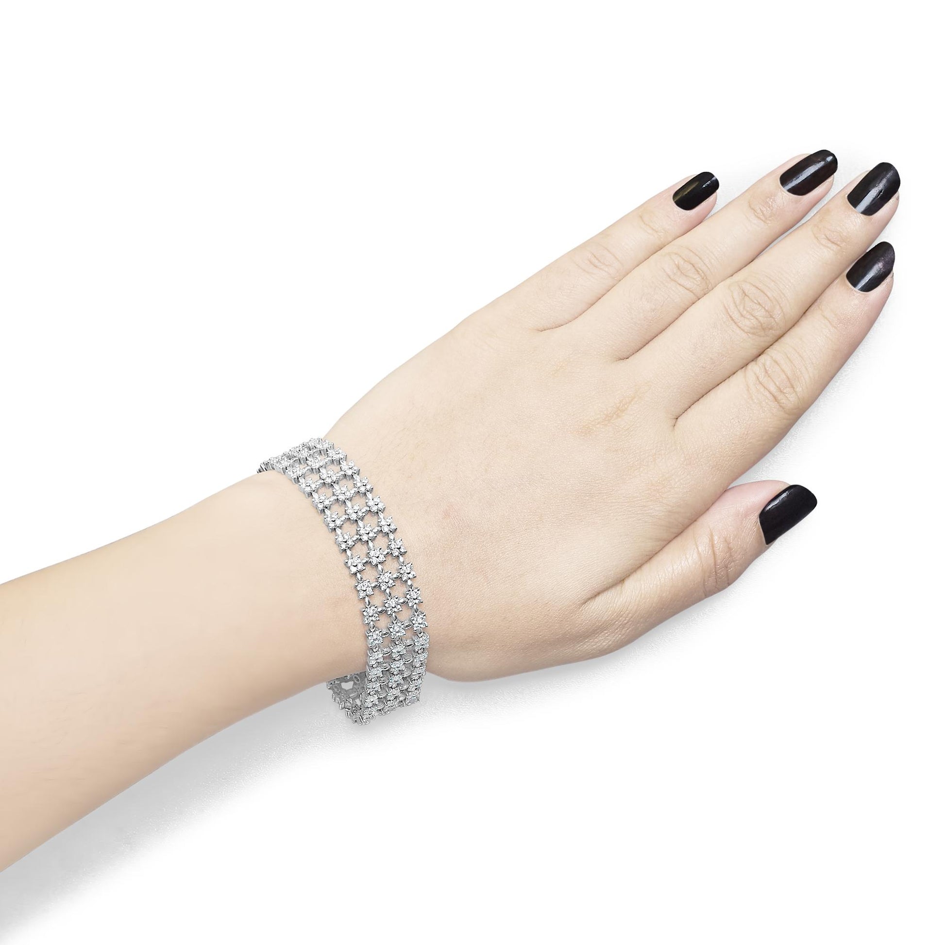 White metal bracelet with multiple rows of round white gemstones in four-prong settings, shown on a model's wrist from a top angle.
