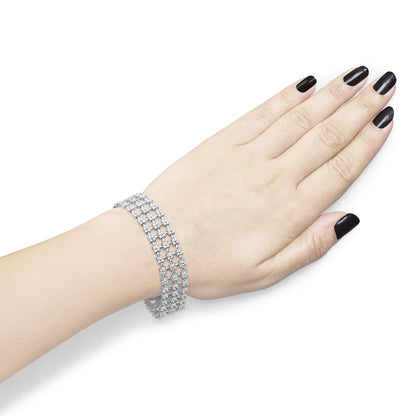 White metal bracelet with multiple rows of round white gemstones in four-prong settings, shown on a model's wrist from a top angle.