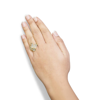 Yellow metal ring with intertwined bands featuring white round and baguette channel-set gemstones, worn on a hand, top-down angle.
