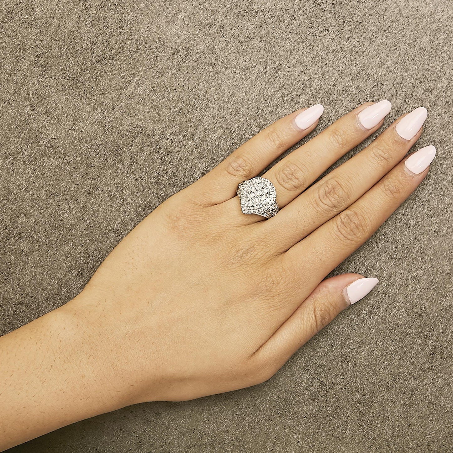 White metal ring with round and baguette white gemstones in prong and channel settings, worn on model's finger, top-angle view.