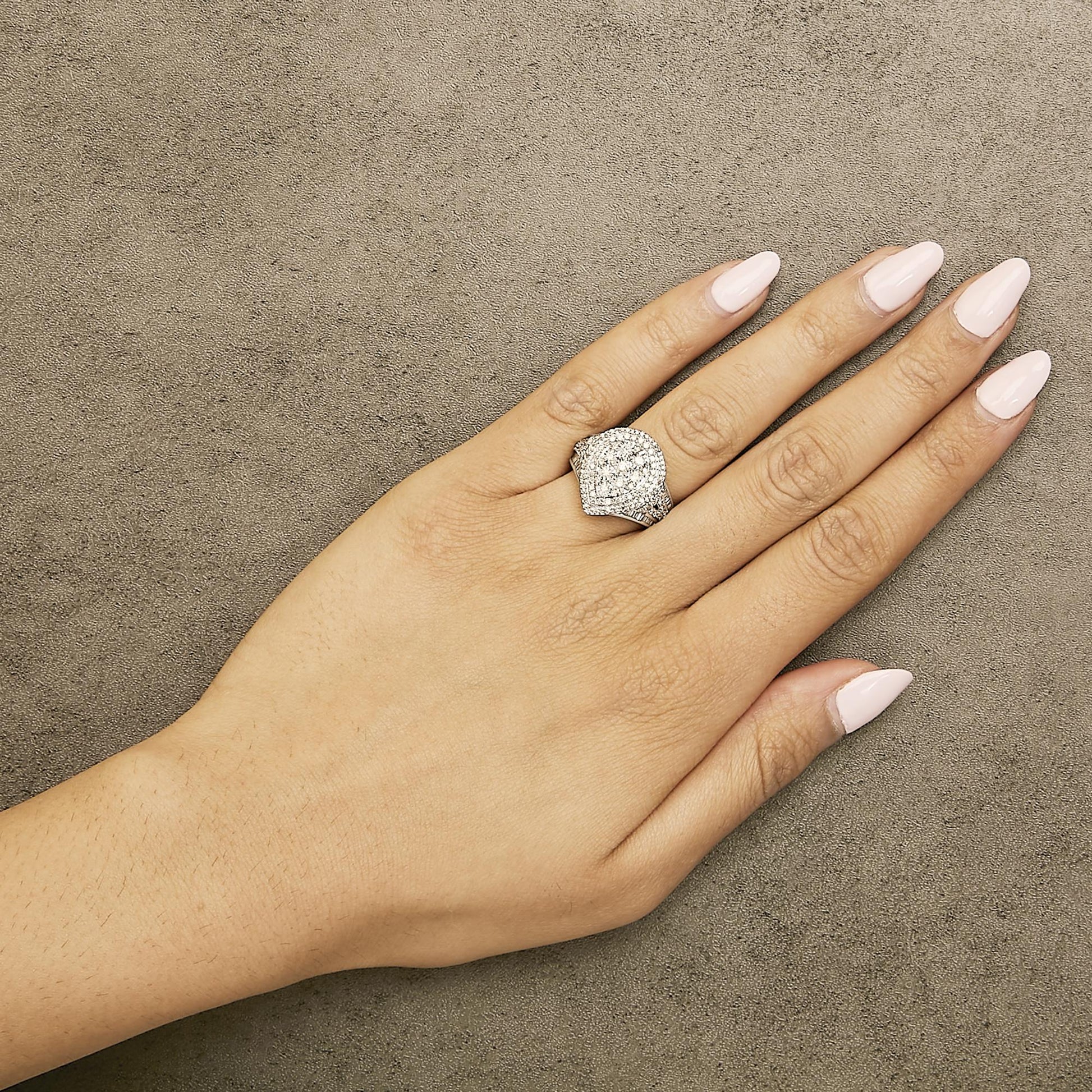 White metal ring with round and baguette white gemstones in prong and channel settings, worn on model's finger, top-angle view.