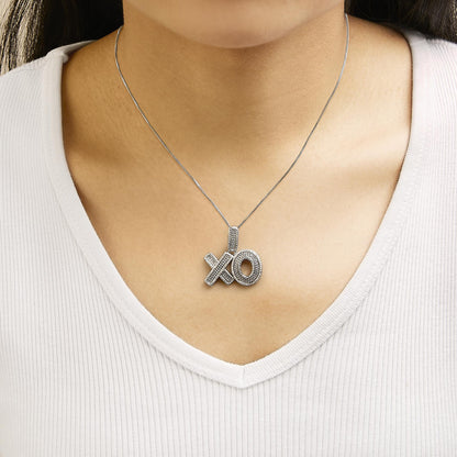 White metal necklace with 'XO' pendant featuring round white gemstones in prong settings, shown worn on a model, front-facing angle.