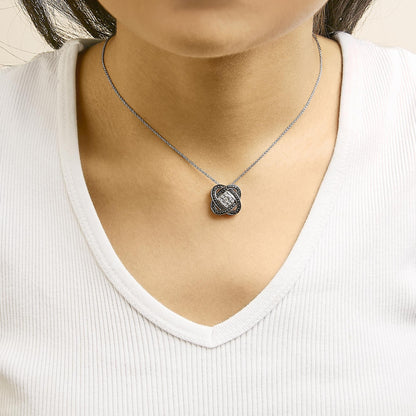Close-up front view of a model wearing a necklace with a black and white metal intertwined knot pendant featuring black pave-set round gemstones and a white invisibly-set round gemstone in the center.