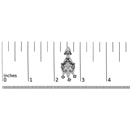 Earring with intricate white and black metal scrollwork, featuring square and round white gemstones, shown on a ruler for scale from a top-down angle.