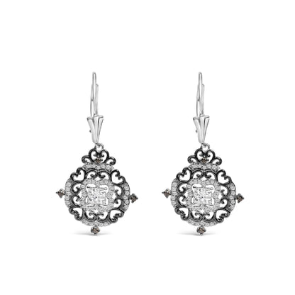 Front view of a pair of drop earrings with an intricate circular design featuring black and white metal colors, white round gemstones in shared prong setting, white princess-shaped gemstones in invisible setting at the center, and black round gemstones in prong setting accenting the design.
