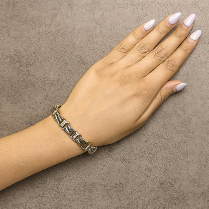 Bracelet with yellow, white, and black metal links featuring black pave-set round gemstones and white shared prong-set round gemstones, shown worn on a model's wrist from a top-down angle.