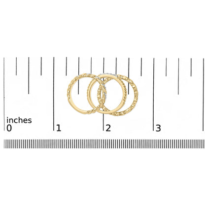 Three yellow and white metal rings, one with round white gemstones in pave setting, shown on a ruler scale from a top flat angle.