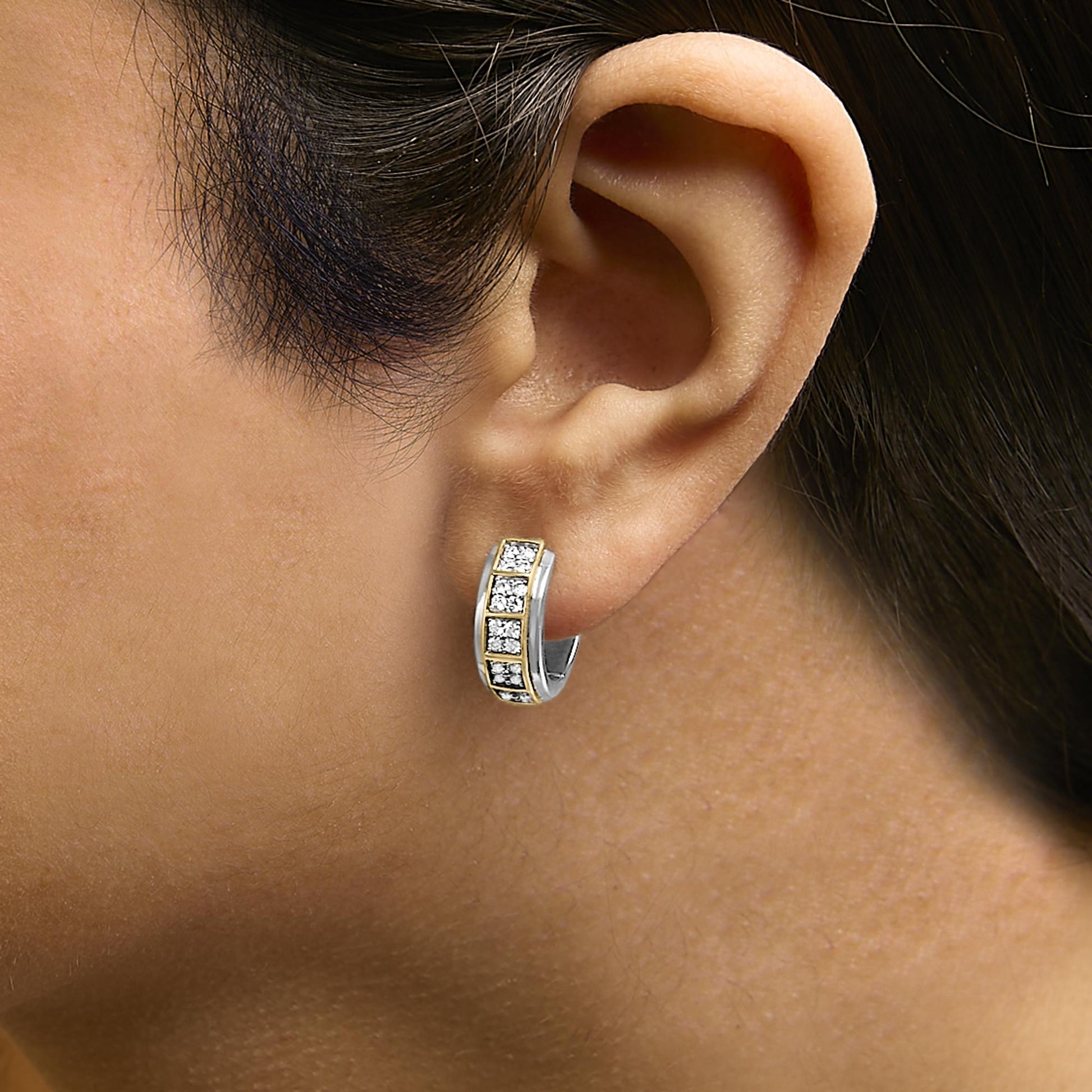 Close-up side view of a hoop earring shown worn on a model's ear, featuring alternating yellow and white metal with a row of round white gemstones set in prongs along the front.