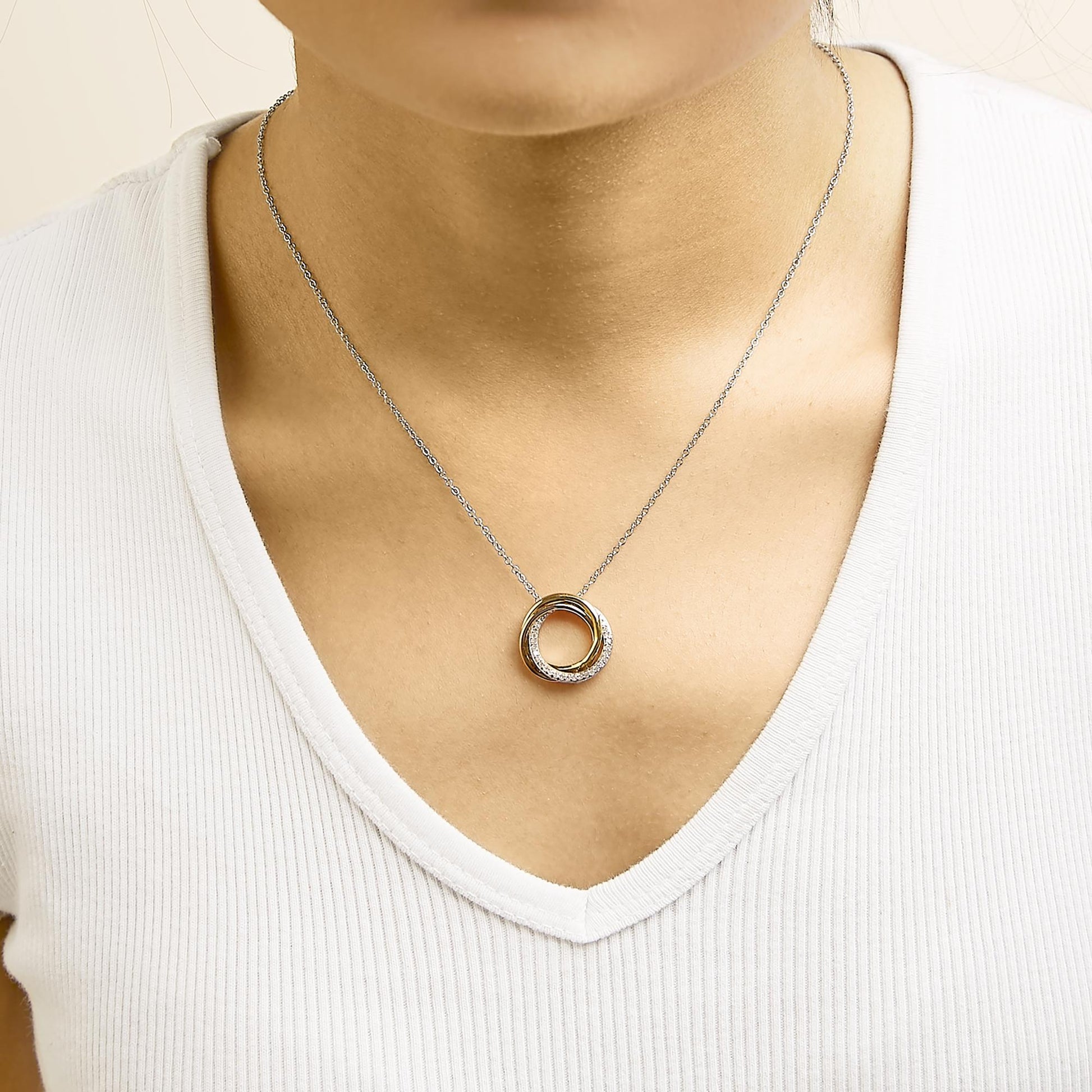 Necklace shown worn on a model, featuring a circular pendant with intertwined bands, one band set with round white gemstones in shared prong settings, shot from the front.