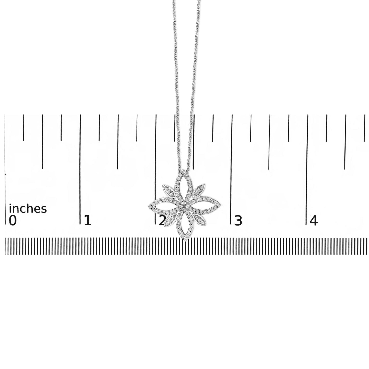 Close-up front view of a white metal necklace with a flower-shaped pendant adorned with round white gemstones in prong settings, shown hanging against a ruler scale background.