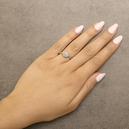 White metal ring with round white gemstones in prong setting forming a circular cluster, shown worn on a model hand from a top-down angle.