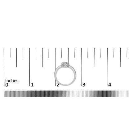 White metal ring with round white gemstones in prong settings on the band and cluster top, shown from the side on a ruler scale.