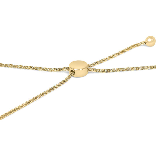 Close-up angled view of a yellow metal bracelet with woven chain detail and a smooth round slider clasp.