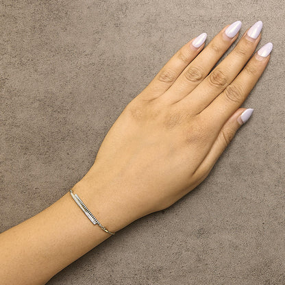 Yellow bracelet with two parallel bars, one with white round pave gemstones, shown worn on a model's wrist from a top-down angle.