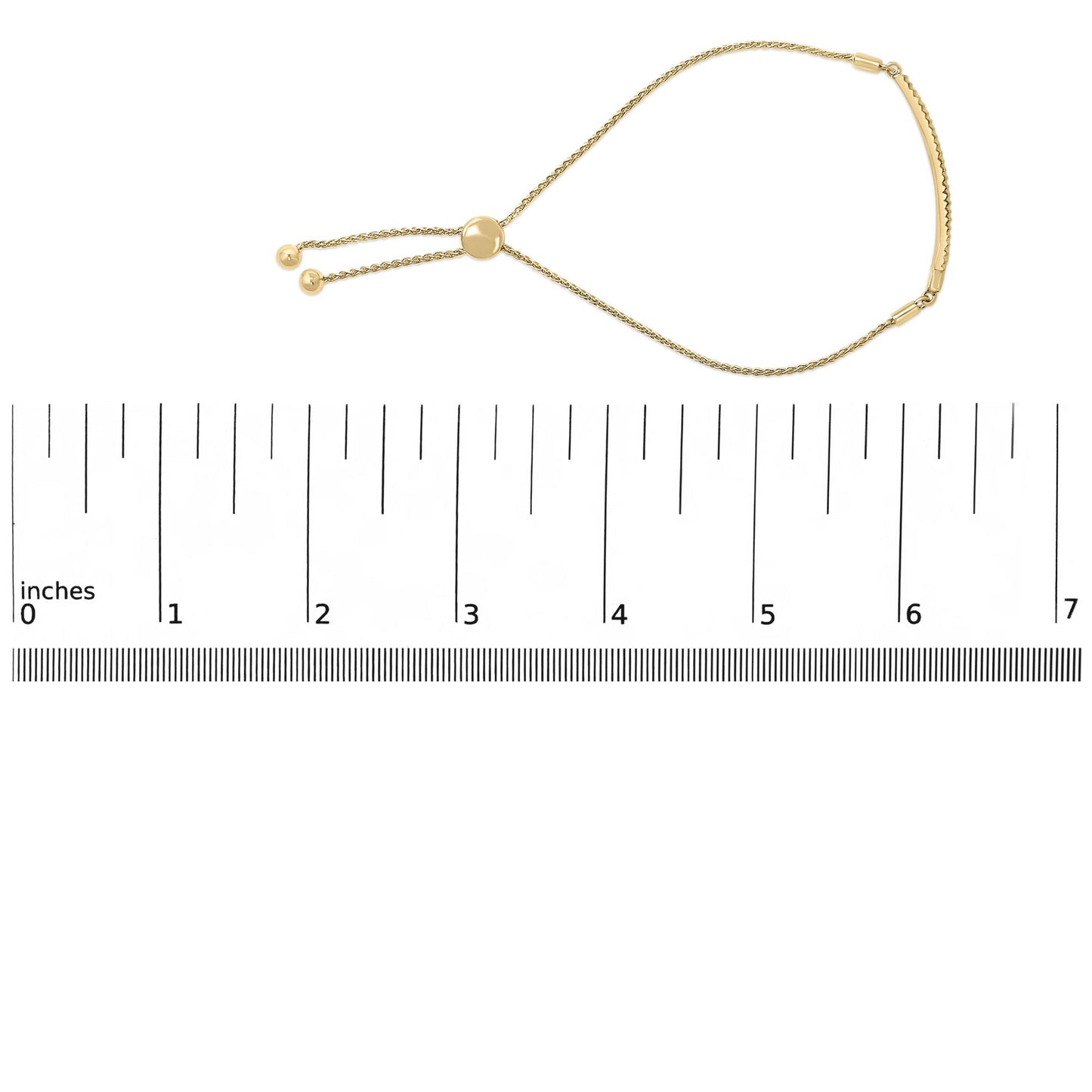 Yellow metal bracelet with round white gemstones in pave setting, shown flat on a ruler, photographed from above at a slight angle.