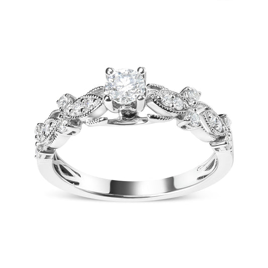 Front angle view of a white metal ring with a round white gemstone in a four-prong setting at the center, flanked by alternating clusters of round white gemstones in three-prong and shared prong settings along the band.