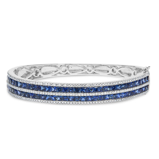 White metal bracelet with three rows of blue square-shaped gemstones channel set, separated by rows of small round white gemstones in four-prong settings, shown from a slightly angled front view.