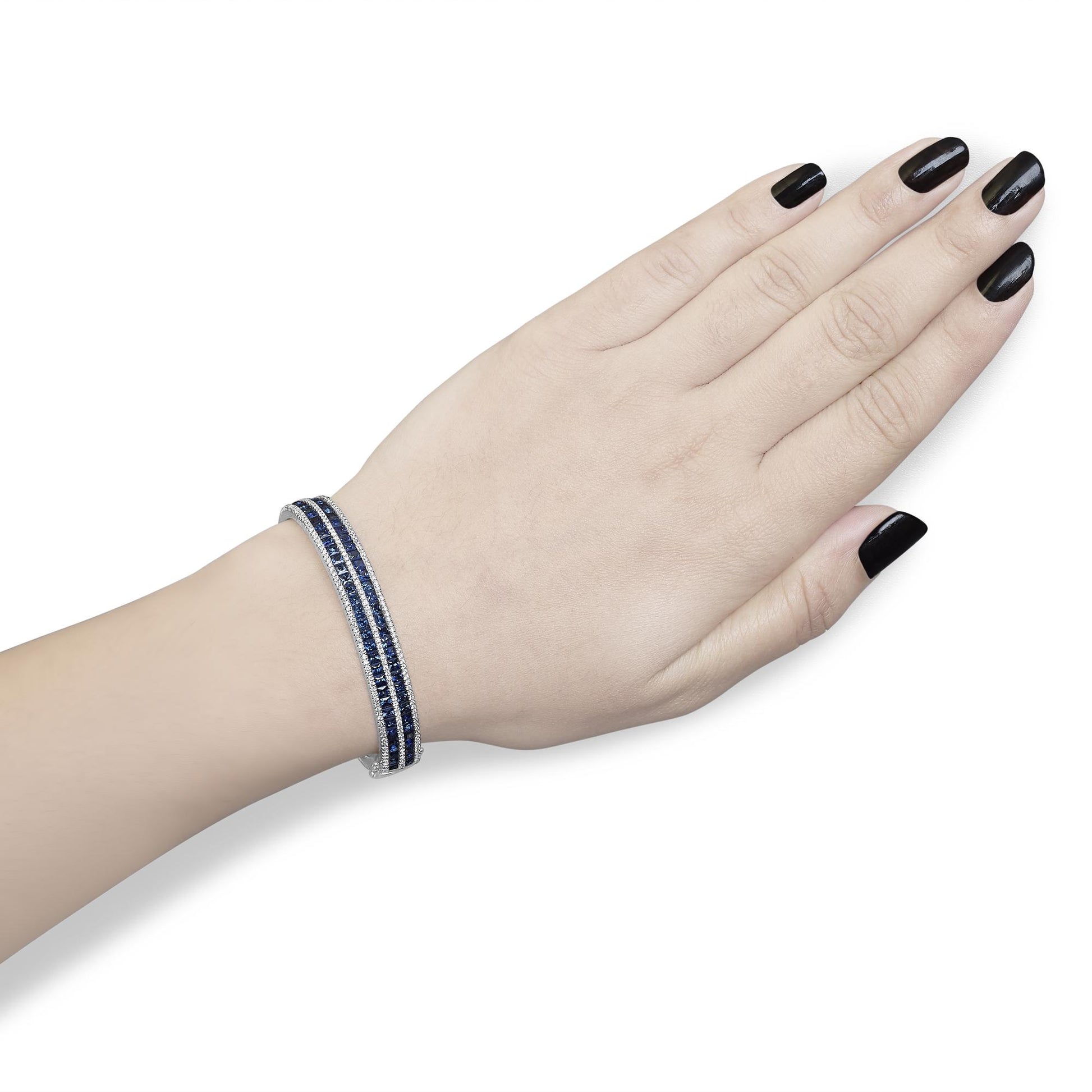 White metal bracelet with two rows of blue gemstones in channel setting bordered by rows of white round gemstones in prong setting, shown on a model's wrist from a top angle.
