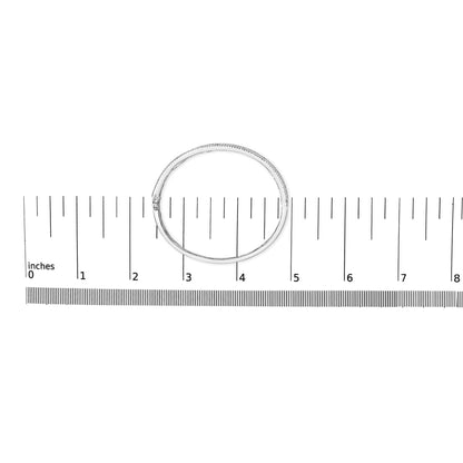 Top-down view of a white metal bracelet with round white gemstones in prong settings and blue square-shaped gemstones in channel settings, placed on a ruler for size reference.