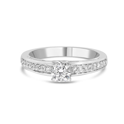 Front angle view of white metal ring with a single round white gemstone in 4-prong setting and additional round white gemstones in shared prong setting along the band.
