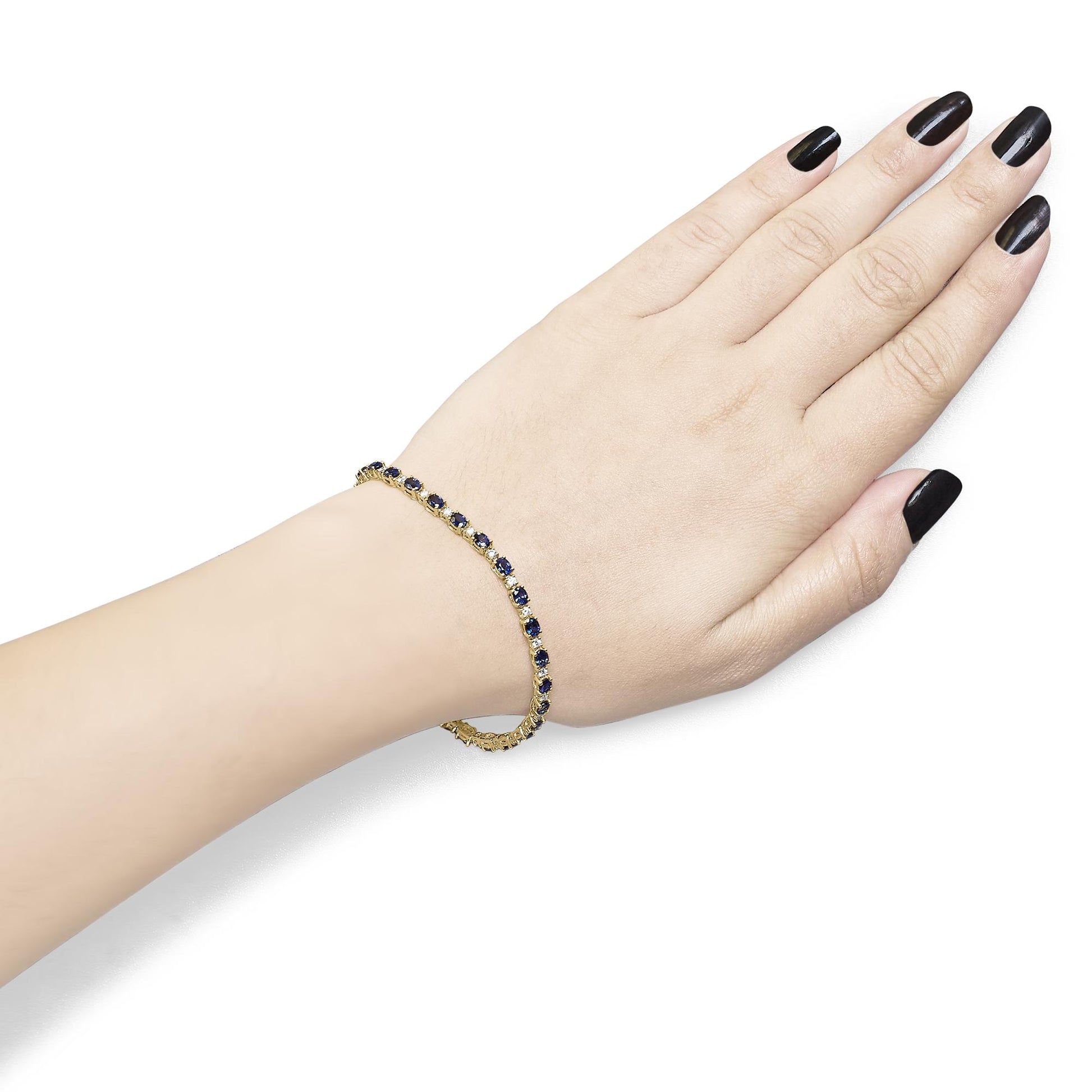 Yellow metal bracelet with alternating white and blue oval gemstones in 4-prong settings, worn on a model's wrist, side angle.