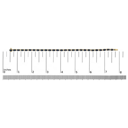 Yellow bracelet with alternating oval blue and round white gemstones in four-prong settings, displayed flat on a ruler for size reference, top-down angle.