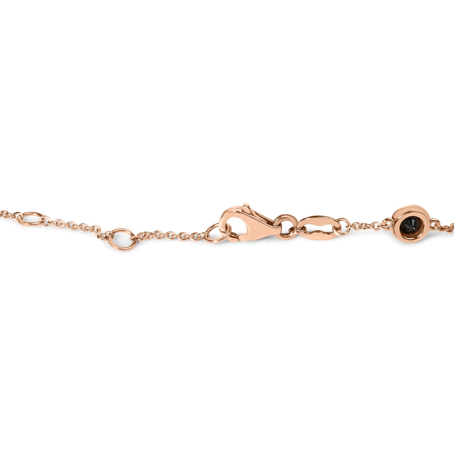 Close-up side angle of a rose metal chain bracelet featuring a clasp and a round black gemstone in a bezel setting.