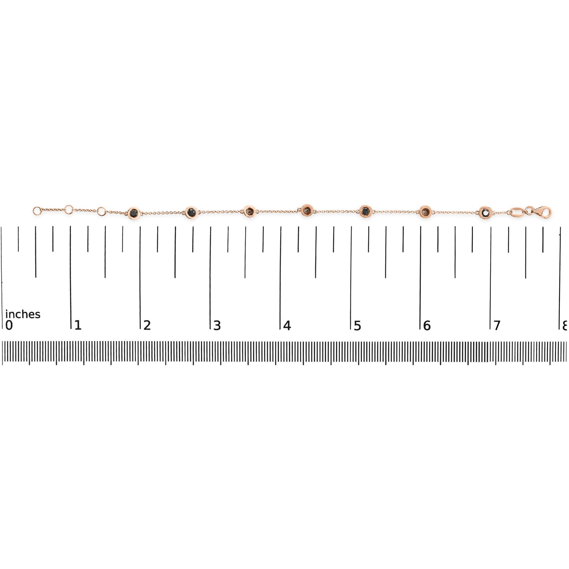 Rose metal bracelet with round black gemstones in bezel settings, laid flat on a ruler for size reference, shot from above.