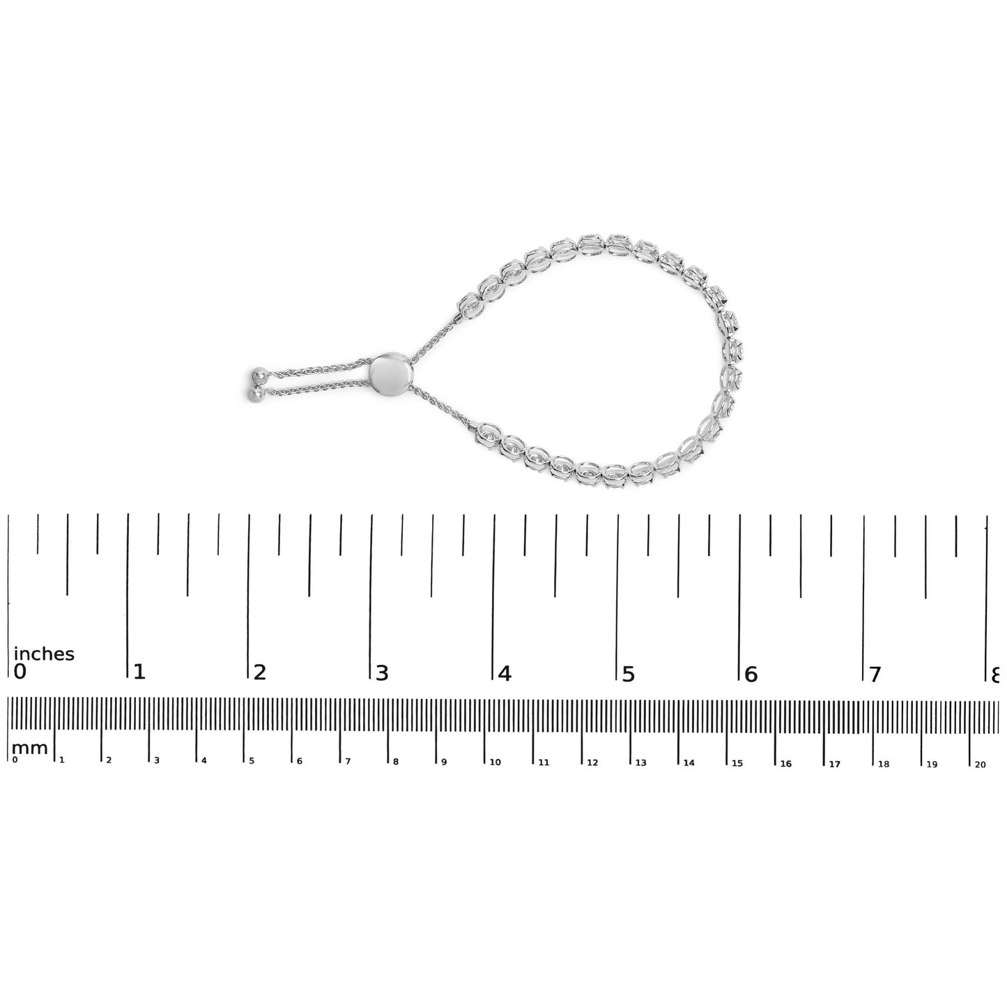 White metal bracelet with round white gemstones in four-prong settings, shown flat on a ruler for size reference, top-down angle.