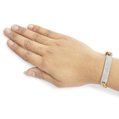Yellow metal bracelet with a rectangular panel of white gemstones in shared prong setting, shown on a model's wrist from a top-down angle.