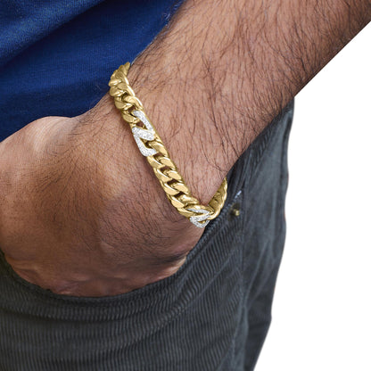 Yellow metal bracelet with large links, some links set with white round gemstones in shared prong setting, shown on a model's wrist from a side angle with their hand in a pocket.