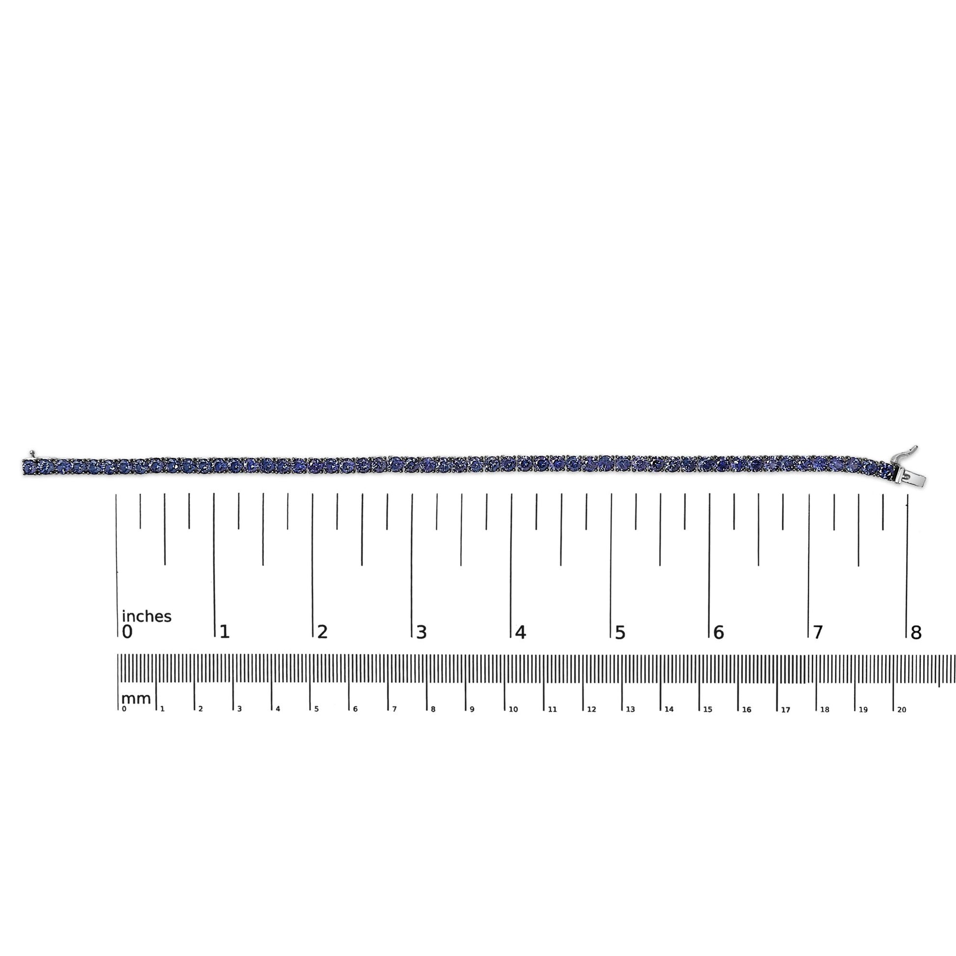 White bracelet with round blue gemstones in a 4-prong setting, shown flat on a scale from a top-down angle.