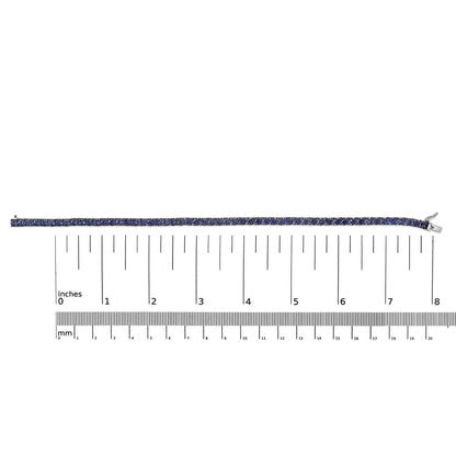 White bracelet with round blue gemstones in a 4-prong setting, shown flat on a scale from a top-down angle.