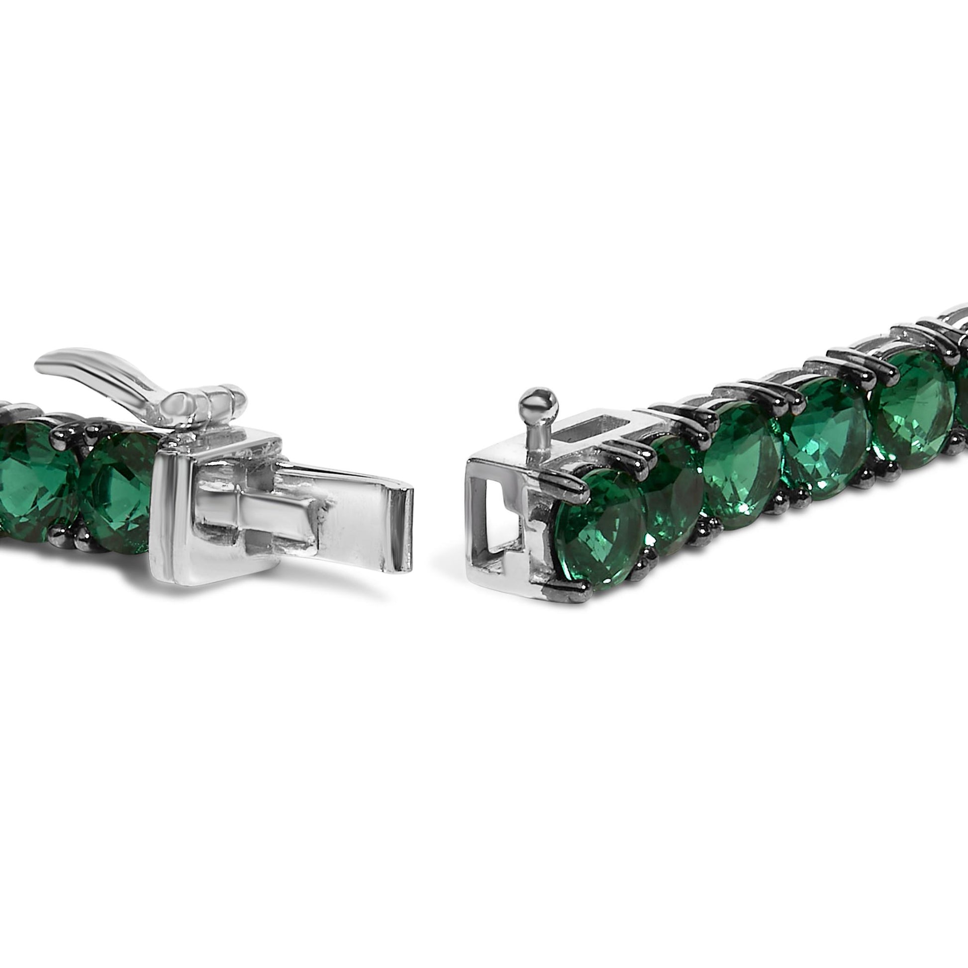 Close-up front angle of a white metal bracelet with round green gemstones set in four-prong settings, showing the open clasp.