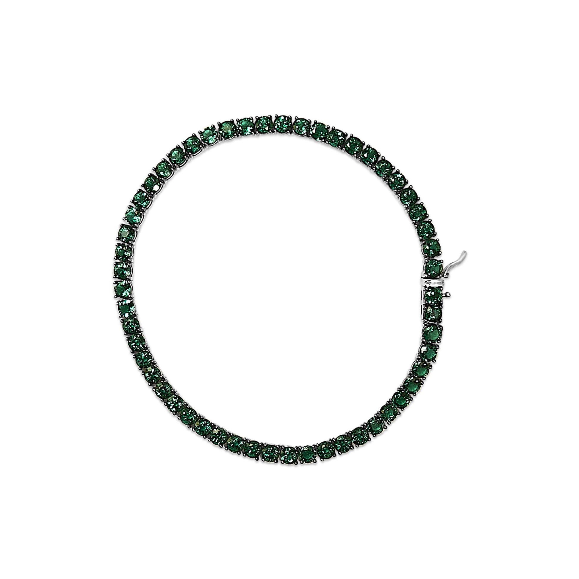 Top-down view of a white bracelet set with round green gemstones in a continuous line with a clasp visible.