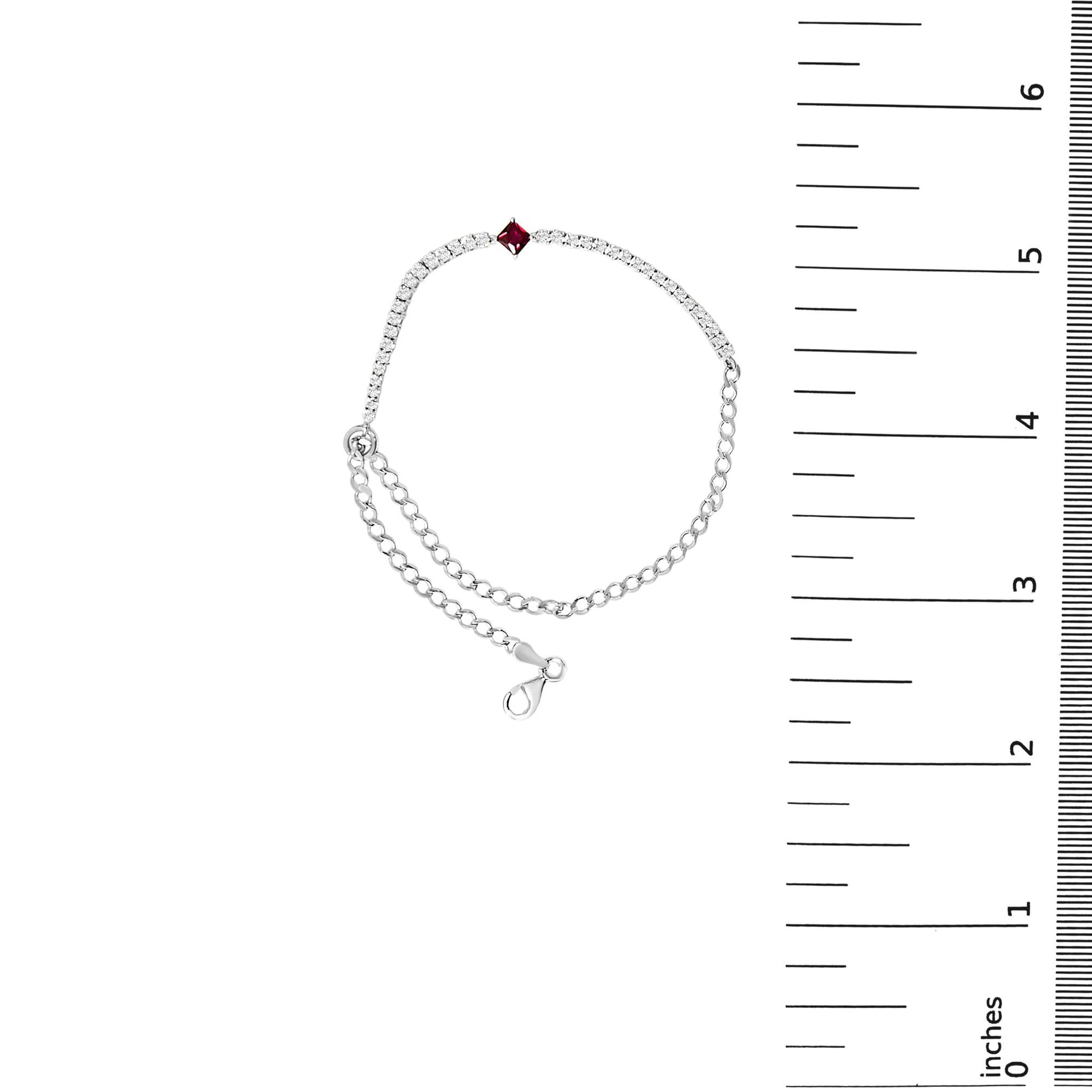 White metal bracelet with a linked chain and a row of round white gemstones set in 4-prong settings, featuring one red square gemstone at the center, shown on a scale from above.