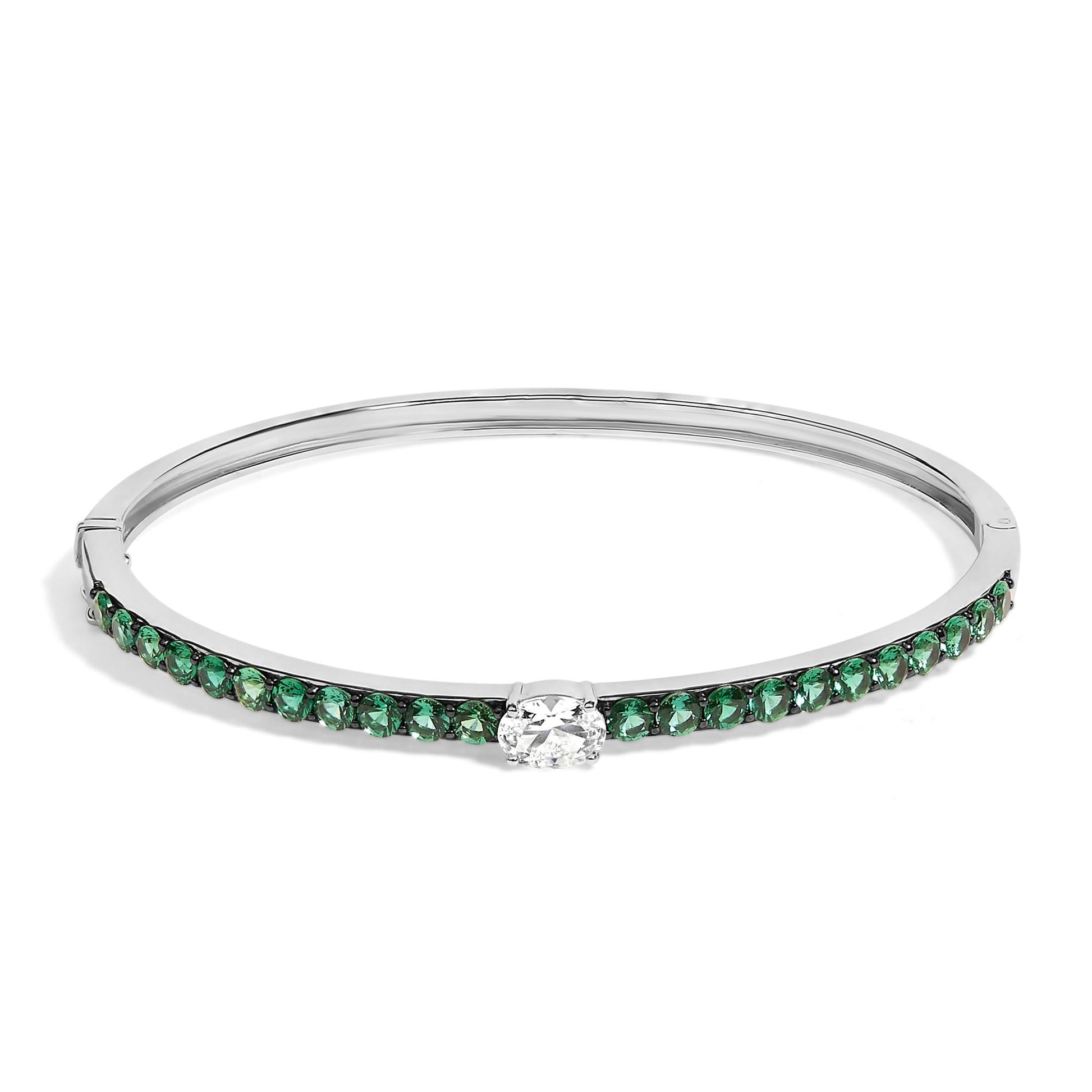 Bracelet with a white metal band, featuring a row of round green gemstones along the front and a single oval white gemstone center-set, shown from a front angle.
