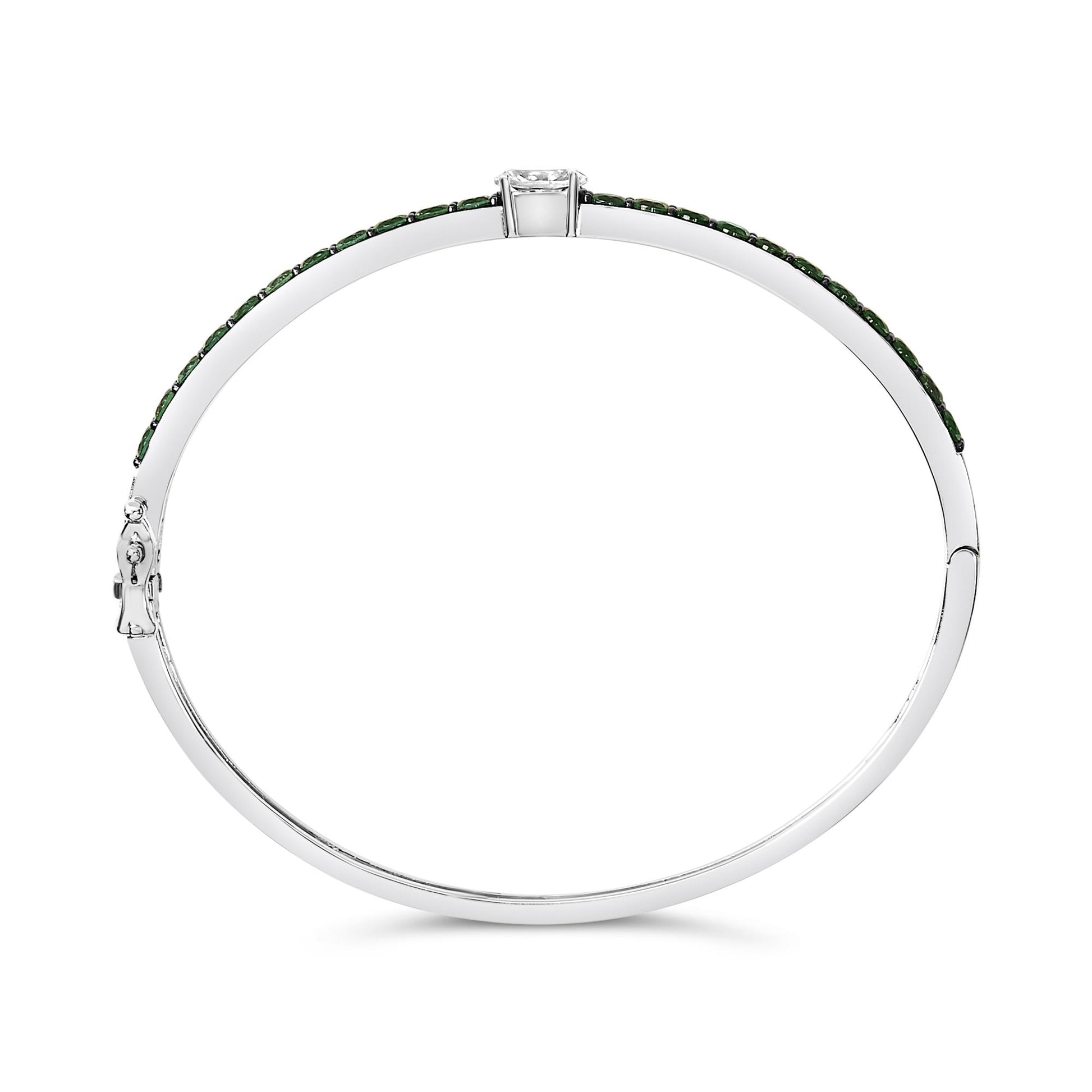 White metal bracelet shown from the top angle on a white background, featuring a single oval white gemstone set in four prongs centered and multiple round green gemstones in shared prong settings along the upper curve.