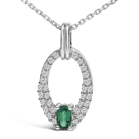 Close-up front angle of a white metal necklace pendant with an oval green gemstone at the bottom center, surrounded by multiple small round white gemstones in a loop design.