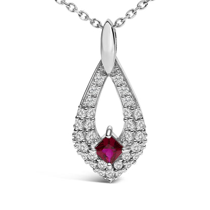 Close-up front view of a white metal necklace pendant with a teardrop shape featuring a princess-cut red gemstone in the center surrounded by multiple round white gemstones, shown on a white background.