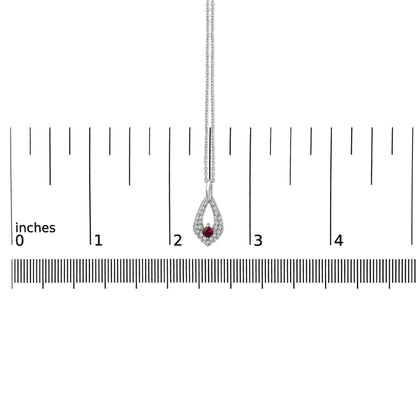 White metal necklace with a teardrop-shaped pendant featuring a central red princess-shaped gemstone surrounded by small white round gemstones, shown hanging on a scale with rulers in the background, front view.