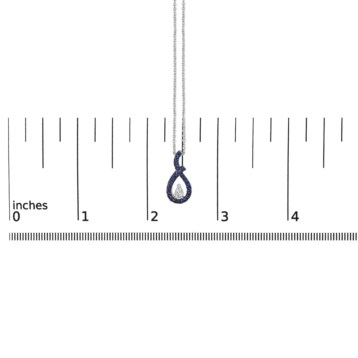 White metal necklace with a loop-shaped pendant featuring a central pear-shaped white gemstone surrounded by round blue gemstones, shown on a scale from a front angle.